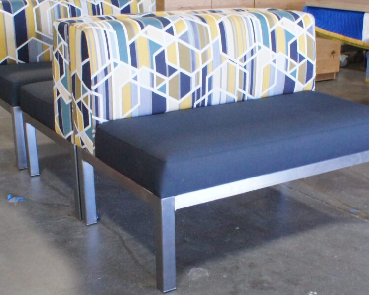 Several banquettes with metal legs in a silver finish. The seats are upholstered in blue fabric and the backs are upholstered in a blue-and-yellow patterned fabric.